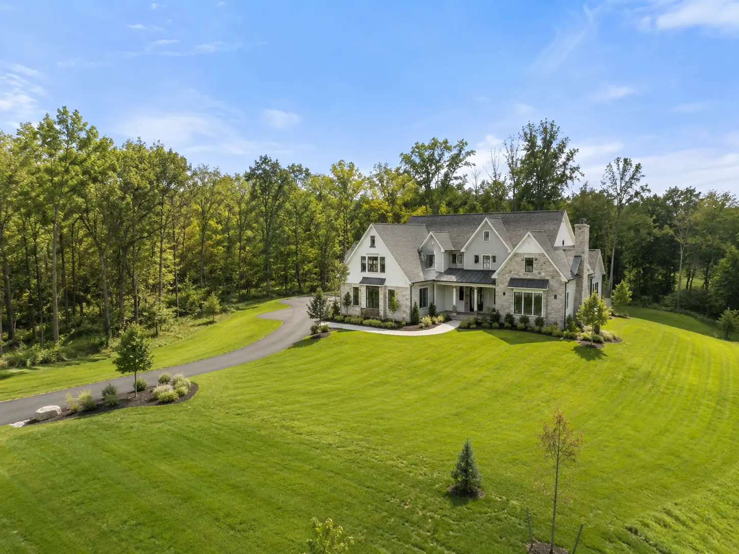 New construction home in Buckingham PA on a large private lot with open lawn, wooded surroundings, and curved driveway